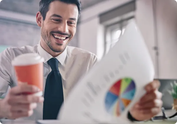 Homem sorrindo segurando um café e um relatório com gráfico