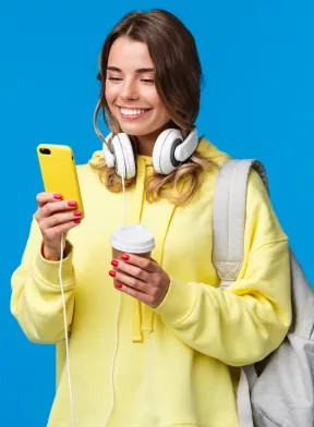 Estudante com fones de ouvido usando o celular e segurando um café