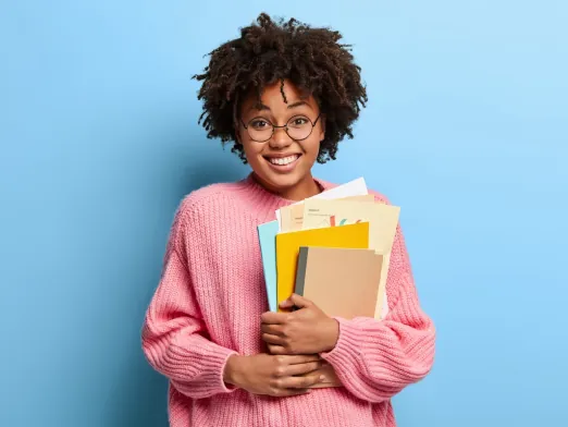 Estudante de óculos sorrindo com cadernos e pastas